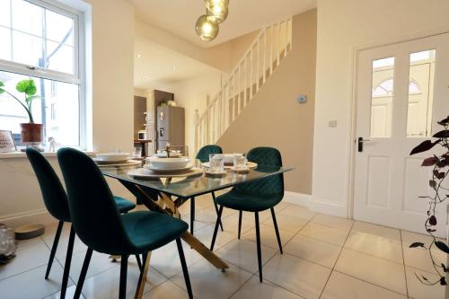 a dining room with a table and green chairs at Spacious 2-Bed Cardiff Haven with Luxe Touches in Cardiff