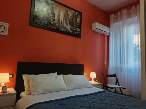 a bedroom with a bed with an orange wall at Adriatic Room 50 m dalla stazione Ferroviaria di Ciampino e dalla navetta aeroportuale in Ciampino