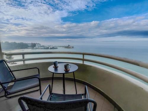 a table and chairs on a balcony with a view of the ocean at 'Sunny Seaview' at Regency corner unit with 2 carpark by Shine Stay in Port Dickson