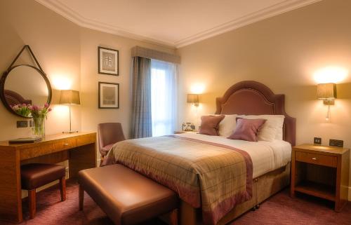 a bedroom with a bed and a desk and a mirror at Bishop's Gate Hotel in Derry Londonderry