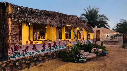 a yellow house with a palm tree in front of it at Almaza Camp in Siwa