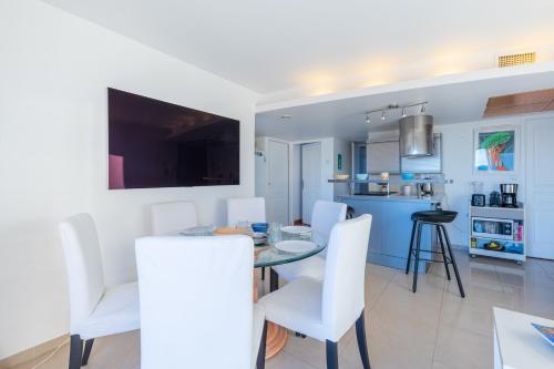 Il comprend une cuisine et une salle à manger avec une table et des chaises blanches. dans l'établissement Appartement Éclat Marin - Welkeys, à Bandol