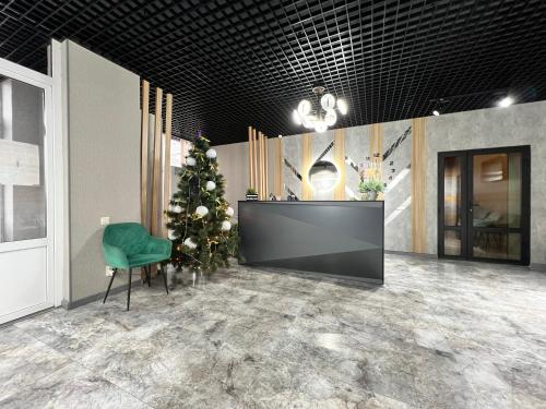 a christmas tree in a lobby with a green chair at Готельно-ресторанний комплекс Поділля in Bershadʼ