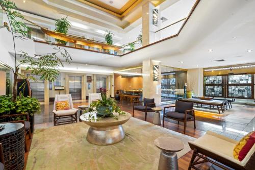 an open lobby with tables and chairs and plants at Luana Waikiki Hotel & Suites in Honolulu