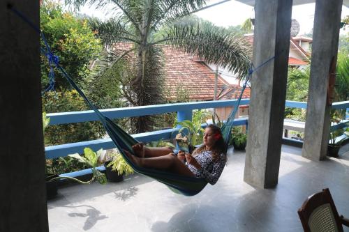 a woman sitting in a hammock on a porch at Costels Mirissa in Mirissa