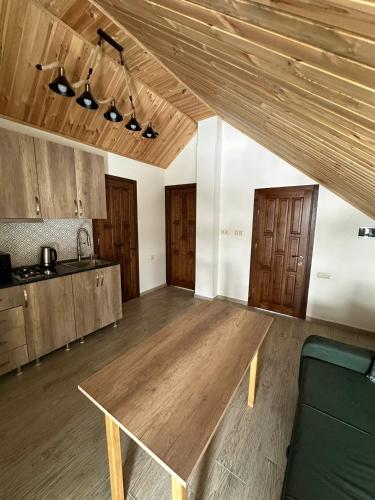 a living room with a wooden table and a kitchen at Bakuriani Cottages in Bakuriani