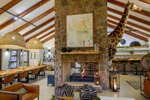 a restaurant with a fireplace with a giraffe on the wall at Umlingo Lodge in Melkrivier