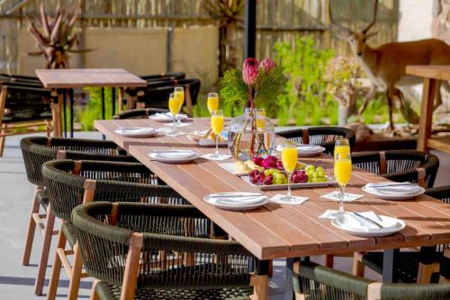 a wooden table with glasses of orange juice and fruit on it at Umlingo Lodge in Melkrivier