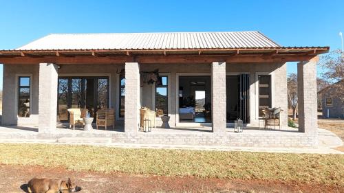 a dog laying on the ground in front of a house at Umlingo Lodge in Melkrivier