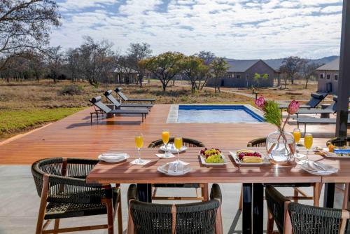 a wooden deck with a table and chairs and a pool at Umlingo Lodge in Melkrivier