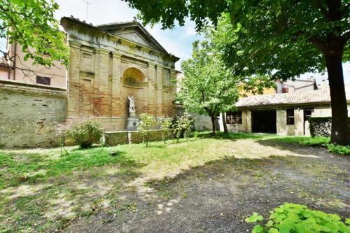 an old brick building with a tree in the yard at Palazzo Alavolini - the loft suite in Fano