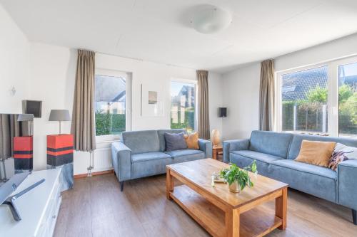 a living room with two blue couches and a coffee table at Villapark Kamperfoelie 75 in De Koog