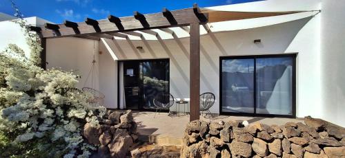 a white house with a wooden pergola at Lajares Villa y estudios Art Lab Fuerteventura in Lajares