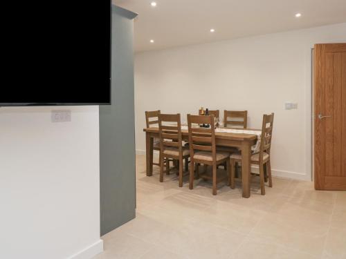 a dining room with a table and chairs and a flat screen tv at Apple Tree Barn in Dalton in Furness