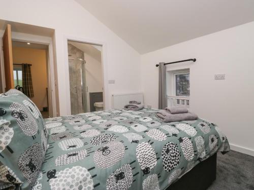 a bedroom with a bed with a green and white comforter at Apple Tree Barn in Dalton in Furness
