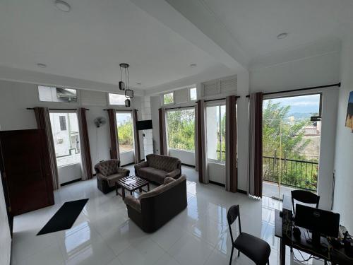 a living room with a couch and chairs and windows at Kandy Alpine Breeze in Kandy