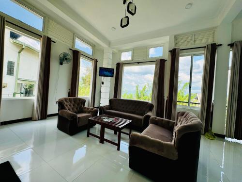 a living room with couches and a table and windows at Kandy Alpine Breeze in Kandy