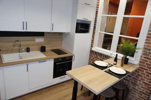 une cuisine avec des armoires blanches et une table en bois dans l'établissement Joli appartement avec cachet dans le Vieux Lille, à Lille