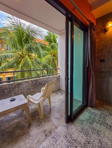 a balcony with a bench and a table and a palm tree at At Home Khaolak in Khao Lak