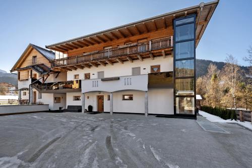 a large white building with a balcony on top at Apartments Antersi Robbi in San Vigilio Di Marebbe