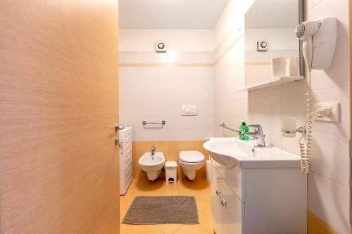 a white bathroom with a toilet and a sink at Night and day 3 in Predazzo