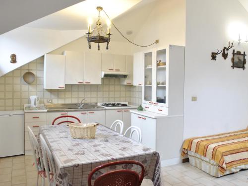 Una cocina con gabinetes blancos y una mesa con sillas. en Appartamenti Le Mongolfiere, en Malè