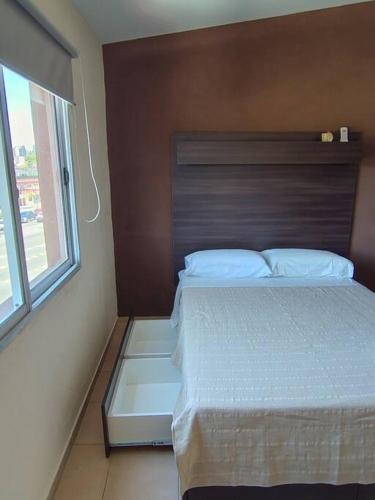 a bedroom with a bed with a wooden headboard and a window at Rooftop Velez Sarsfield in Buenos Aires