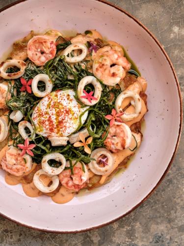 a plate of food with shrimp and greens at RUMA Surf Hotel in Ahangama