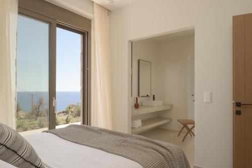 a bedroom with a bed and a large window at VK Villas - Votsalo & Kyma Villas, By ThinkVilla in Léntas