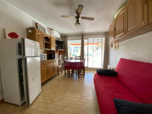 un salon avec un canapé rouge et une cuisine dans l'établissement Sol-y-Days Los Amigos, Studio 4 couchages en rez-de-jardin, avec grande terrasse et parking, à 250m de la plage, au Grau-du-Roi