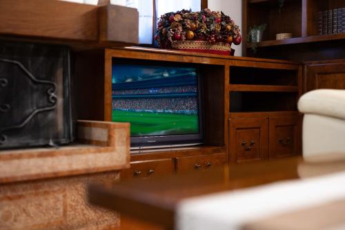 a television in a wooden entertainment center with a soccer game at Fuori da ZTL - Asiago a due passi da tutto in Asiago