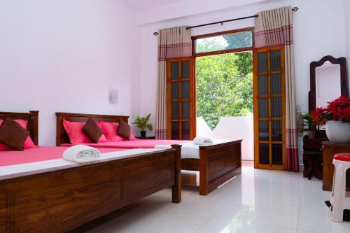 a bedroom with two beds and a large window at Flower Top Ella in Ella