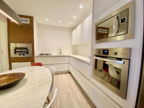 a white kitchen with a table and a dining room at RCM Vilas - Porto Picarras in Piçarras