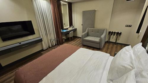a hotel room with a bed and a chair and a television at VE Hotels Adakale in Yenişehir