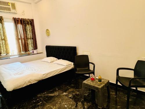 a bedroom with a bed and two chairs and a table at Vivanta Home Stay in Ayodhya