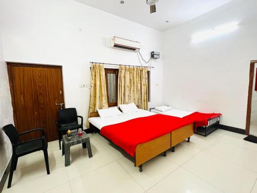 a bedroom with a red bed and a chair at Vivanta Home Stay in Ayodhya