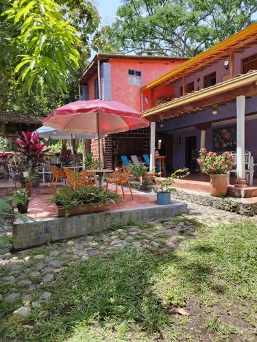 a patio with a table and an umbrella in front of a house at Selvablanca Hostel in San Jerónimo