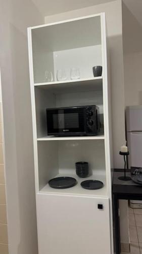 a white cabinet with a microwave in a kitchen at Appartement au Plessis-Robinson in Le Plessis-Robinson