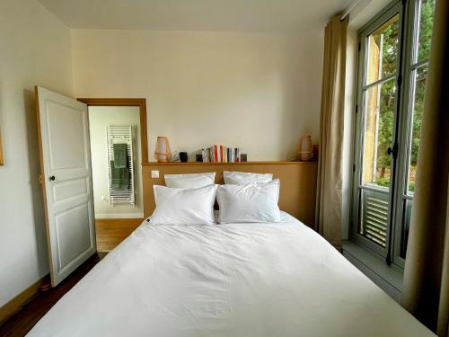 a bedroom with a white bed and a window at Le Ginkgo in Autun