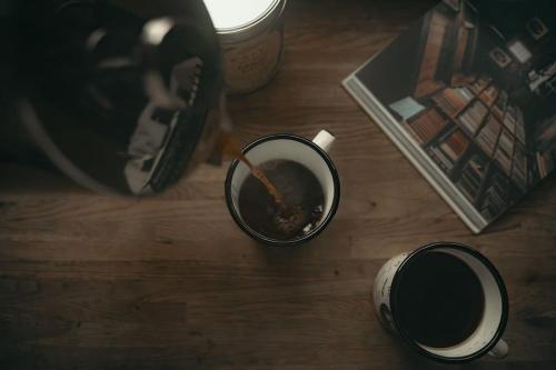 a cup of coffee on a wooden table with a bowl of food at Briežu Stacija Off Grid Cabin in Līgatne