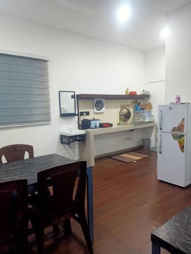 a kitchen with a table and a white refrigerator at D'semporna Homestay in Semporna
