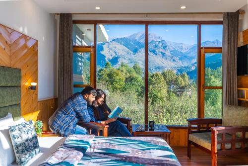 2 persone sedute in una stanza con vista sulle montagne di The 14 Gables, A Boutique Stay - Pet Friendly Hotel a Manāli