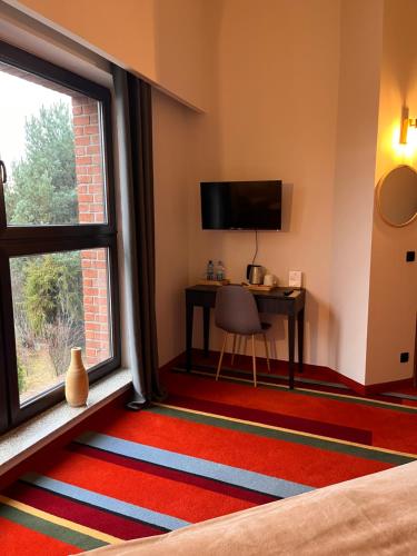 a room with a bed and a desk and a window at Hotel i Restauracja Czarny Kos in Borkowo
