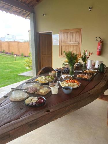 Pousada Vila da Mata - Canastra في ساو جواو باتيستا دو غلوريا: طاولة خشبية طويلة عليها العديد من أطباق الطعام