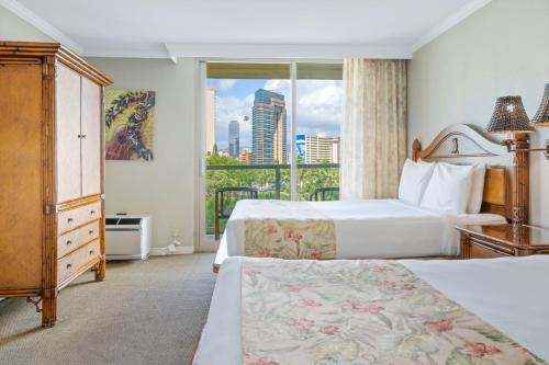 a hotel room with two beds and a window at Luana Waikiki Hotel & Suites in Honolulu