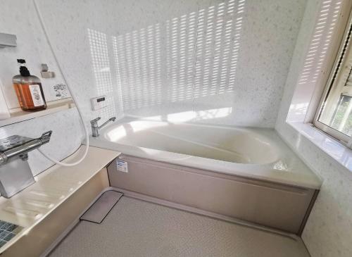 Hokotaにあるパーティーができるビーチハウス海まで1分一棟貸切Qiao105屋外犬可の窓付きのバスルーム(白いバスタブ付)