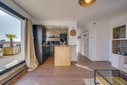 Il dispose d'une cuisine ouverte et d'un salon avec une grande fenêtre. dans l'établissement Le Rooftop - A 10min de Bordeaux centre, à Talence