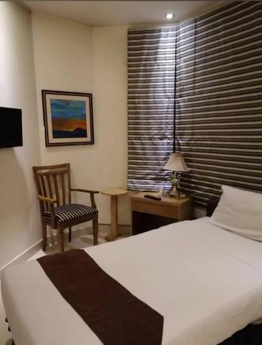 a bedroom with a bed and a chair and a desk at Panoramic Hotel Lahore in Lahore