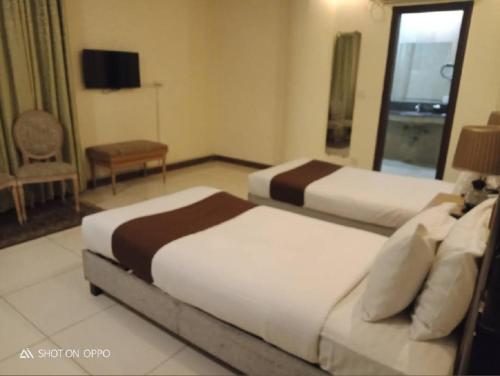 a hotel room with two beds and a television at Panoramic Hotel Lahore in Lahore