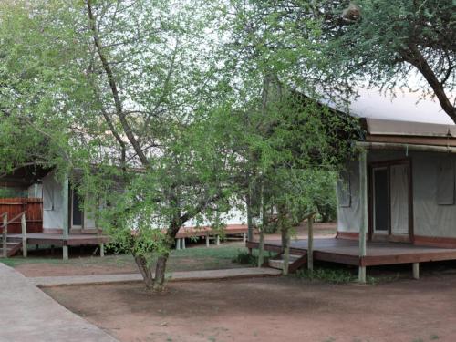 a building with trees and benches in front of it at Ngata Safari Lodge in Hammanskraal